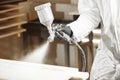 Close-up of industrial worker using paint gun or spray gun for applying paint, airless spraying. Royalty Free Stock Photo