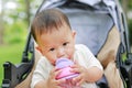 Close-up infant baby boy sitting on stroller and drinking water from Baby sippy cup with straw Royalty Free Stock Photo