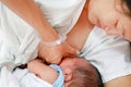 Close-up infant baby feeding from mother breastfeeding her newborn child on the hospital bed