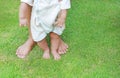 Close up infant baby feet learning to walk with his mother on the green grass. First steps Royalty Free Stock Photo