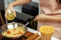 Close up influencer cooking spaghetti mix ingredient to frying pan. Postulate. Royalty Free Stock Photo