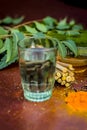 Close up of ingredients of ayurvedic treatment i.e neem,neem leaves,neem powder,bark,clove,turmeric,water.