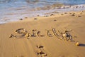 Close-up of inscription word Sicily written on wet sand of beach seashore coastline after tide near waves at sunset. Royalty Free Stock Photo