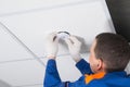 Close-up of the installation of a motion sensor for lighting automation, with hands in protective gloves of an electrician