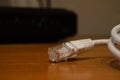 Close up of internet cable on wooden table with modem in the background Royalty Free Stock Photo