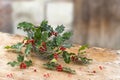 Close up iron, basket of holly red berries branches, grean leaves, evergreen, on rustic, table over a , vintage ambiance