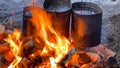 Close-up of iron pots of water over a large fire. Travel kitchen. Yellow-orange flames. Burning firewood and logs Royalty Free Stock Photo