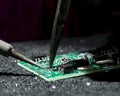 Soldering iron and tool on green circuit board