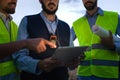 Close up of irrecognizable group of engineers and maintenance workers looking at digital tablet together discuss plans.