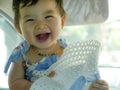 Close up isolated face portrait of sweet and adorable Asian Chinese baby girl laughing and smiling cheerful holding hat enjoying Royalty Free Stock Photo