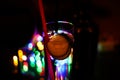 Close up of isolated gin tonic cocktail glass with slices of cucumber and pink plastic straw. Vibrant colorful bokeh and blurred