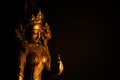 Close up of isolated illuminated hindu Shiva god golden bronze statue with raised hand on blank black background