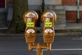 Close up isolated image of two brown vintage coin operated parking meters for up to 2 hours of street parking.