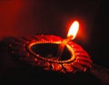 Close up isolated low key diwali oil clay lamp or panti shot with a dutch angle diagonal framing on a dark orange black ba