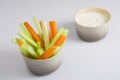 Close up isolated shot of a mixed bowl of crunchy orange carrot slices and juicy green celery sticks with a white cup of blue Royalty Free Stock Photo