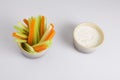 Close up isolated shot of a mixed bowl of crunchy orange carrot slices and juicy green celery sticks with a white cup of blue Royalty Free Stock Photo