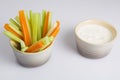 Close up isolated shot of a mixed bowl of crunchy orange carrot slices and juicy green celery sticks with a white cup of blue Royalty Free Stock Photo