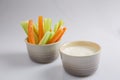 Close up isolated shot of a mixed bowl of crunchy orange carrot slices and juicy green celery sticks with a white cup of blue Royalty Free Stock Photo