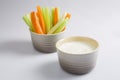 Close up isolated shot of a mixed bowl of crunchy orange carrot slices and juicy green celery sticks with a white cup of blue Royalty Free Stock Photo