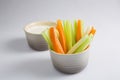 Close up isolated shot of a mixed bowl of crunchy orange carrot slices and juicy green celery sticks with a white cup of blue Royalty Free Stock Photo