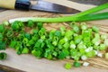 Close up of isolated sliced fresh spring onions scallions on wooden olive tree cutting board and japanese kitchen knife Royalty Free Stock Photo