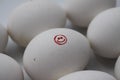 Close up of isolated white raw egg with painting of red smiling face surrounded by group of equal eggs focus on face Royalty Free Stock Photo