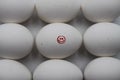 Close up of isolated white raw egg with painting of red smiling face surrounded by group of equal eggs focus on face Royalty Free Stock Photo