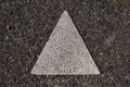 Close up of a isosceles triangle painted with thick white paint on the asphalt