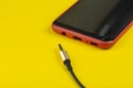 Close-up Jack plug and a cable with phone on a yellow background Royalty Free Stock Photo