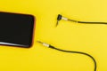 Close-up Jack plug and a cable with phone on a yellow background Royalty Free Stock Photo