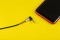 Close-up Jack plug and a cable with phone on a yellow background Royalty Free Stock Photo