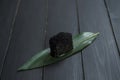 Close up of Japanese Black Tobiko Caviar Gunkan Sushi on bamboo leaf, dark wooden board.