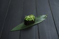 Close up of Japanese Gunkan Maki Sushi roll with Hiyashi wakame chuka and sesame seeds on bamboo leaf, wooden board.