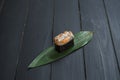 Close up of Japanese Gunkan Maki Sushi with salmon and tobiko caviar on bamboo leaf on black wooden board.