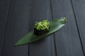 Close up of Japanese Gunkan Maki Sushi roll with Hiyashi wakame chuka and sesame seeds on bamboo leaf, wooden board.