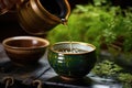 close-up of a japanese teapot pouring green tea into a ceramic cup