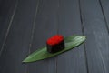 Close up of Japanese Tobiko Caviar Gunkan Sushi on bamboo leaf, dark wooden board.