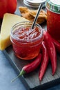 A jar of hot pepper jelly surrounded by peppers, cheese and crackers. Royalty Free Stock Photo