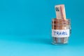 close up of a jar with travel label filled with paper money euro and blue plain background Royalty Free Stock Photo