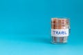 close up of a jar with travel label filled with paper money euro and blue plain background Royalty Free Stock Photo