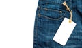 Close-up jeans with blank cardboard white price tag for your text. Label white price tag mock-up on blue jeans. Royalty Free Stock Photo