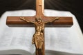 Close-up of Jesus Chris on wood cross ahead of blurred open Bible Royalty Free Stock Photo