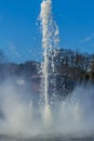 Close up of the jet of a fountain in a park with trees in the background Royalty Free Stock Photo