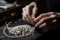 close-up of jeweler's hands, stringing pearls on delicate chain