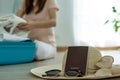 Close up of jewelry, hats, glasses and passports ready to travel. The background picture of women folding clothes packing suitcase