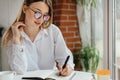 Close-up of a journalist working in a cafe works preparing questions writes down a notebook. Caucasian girl plans the Royalty Free Stock Photo