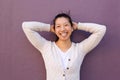 Close up joyful asian woman standing with hands behind head