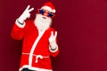 Close up joyful funny playful naughty santa showing peace victory signs, fooling around, in trendy specs, so confident