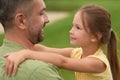 Close up of joyful little girl looking at her happy dad, hugging him while spending time together outdoors on a warm day Royalty Free Stock Photo