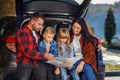 Close up of joyful pleasant family which gethering on their vacation with teen children and using road map to choose the